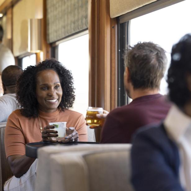 Image of a guest clinking glasses with another guest inside train